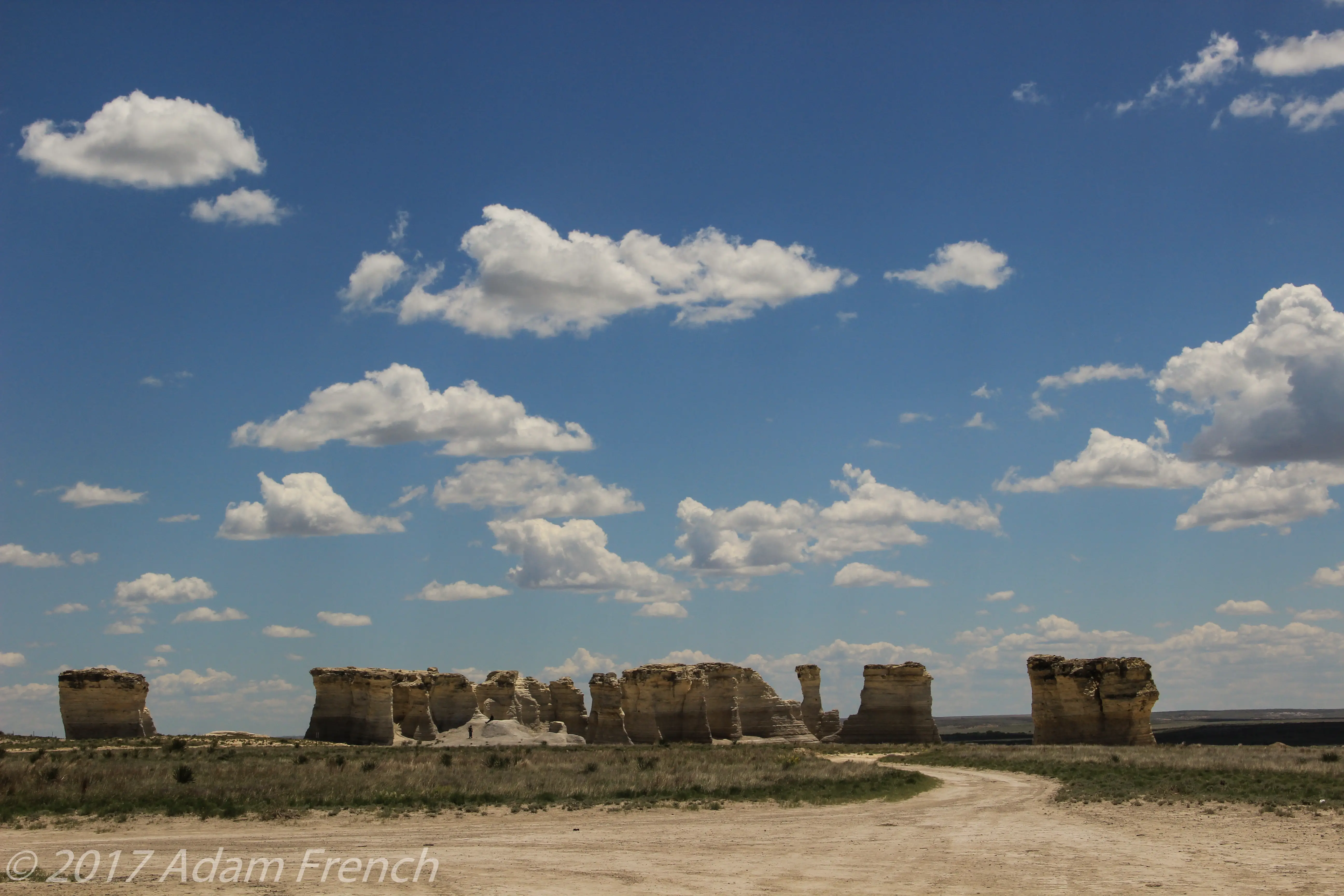 White, rock spires rise from the ground in a sandy, desert-like area