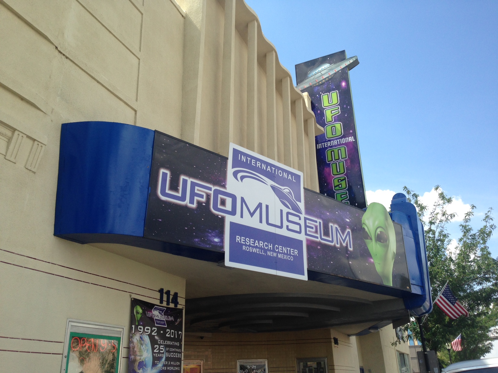 A colorful large sign on a building with a green, alien head. The sign reads, "International UFO Museum Research Center Roswell, New Mexico". 