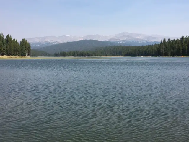 The dark, rippling waters of West Tensleep Lake with rocky mountains looming through the haze in the background