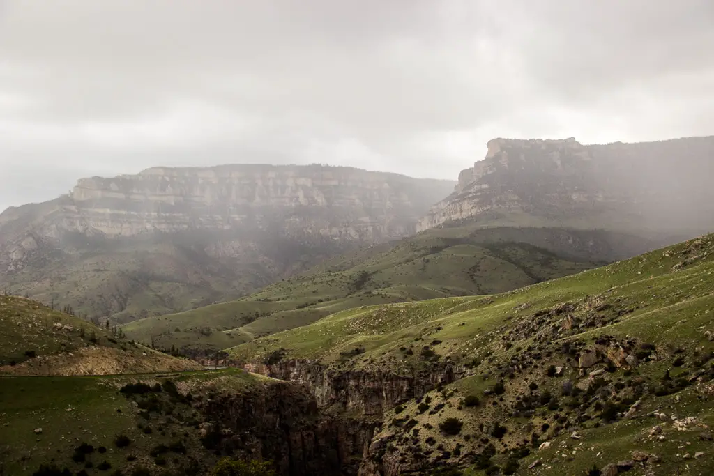 Rocky mountains shrowded in misty rain in the background with green hills in the foreground