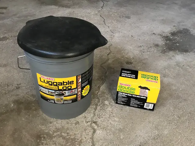 A 5-gallon bucket with lid and a small cardboard box. The bucket has a sticker that reads "luggable loo".