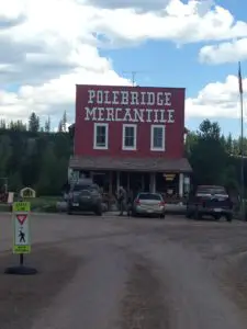 An old storefront with "Polebridge Mercantile" on the front and cars sitting out front