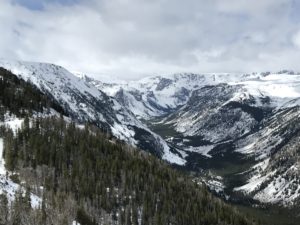 A view over a vista of snow-covered mountains and valleys under a cloudy sky