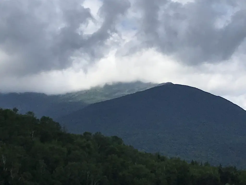 Green, tree-covered mountains cloaked in clouds