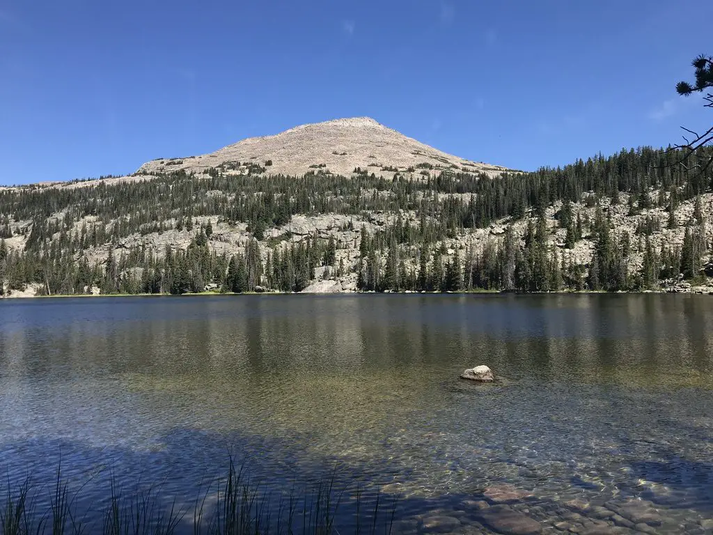 Small lake with rocky, tree-covered mountain peaks in the background