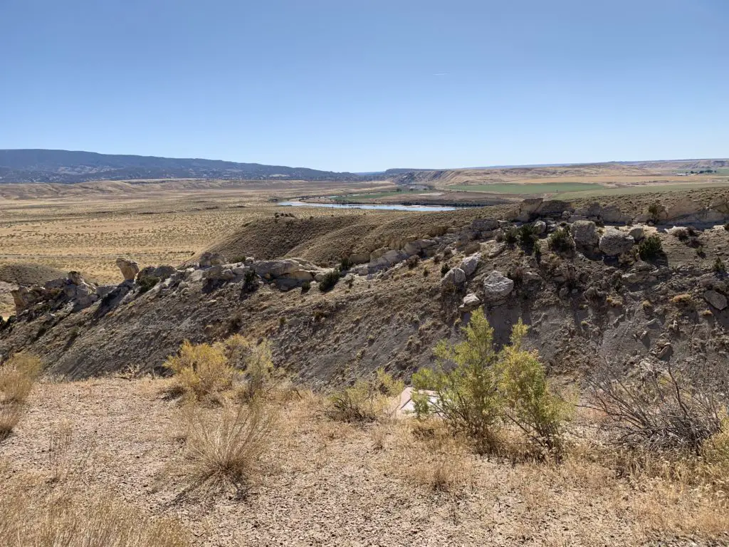 View over a desert landscape. Scrubbrush flatland with a creek in the far background leads to mountains