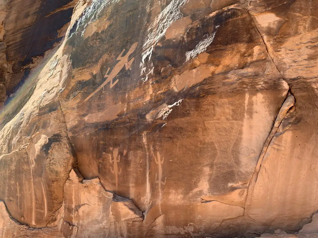 A sandstone, rock wall with etchings of animals