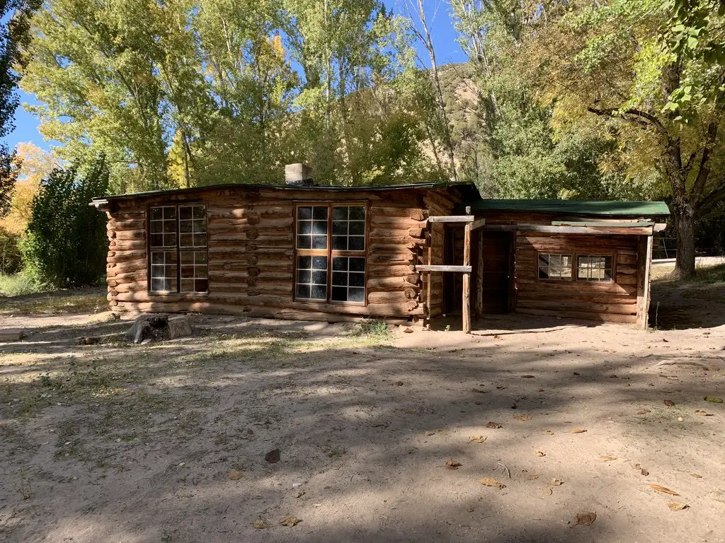 An old, wooden cabin sits amongst trees