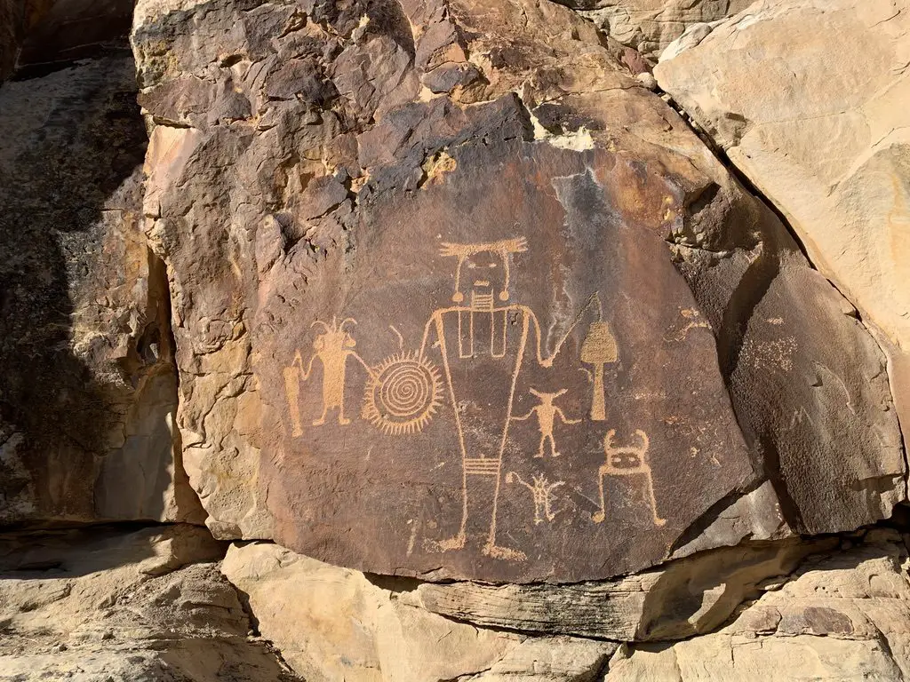 A sandstone, rock wall with etchings of figures