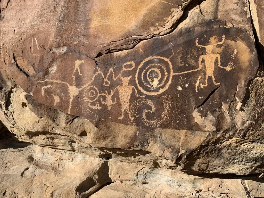 A sandstone, rock wall with etchings of animals and other figures