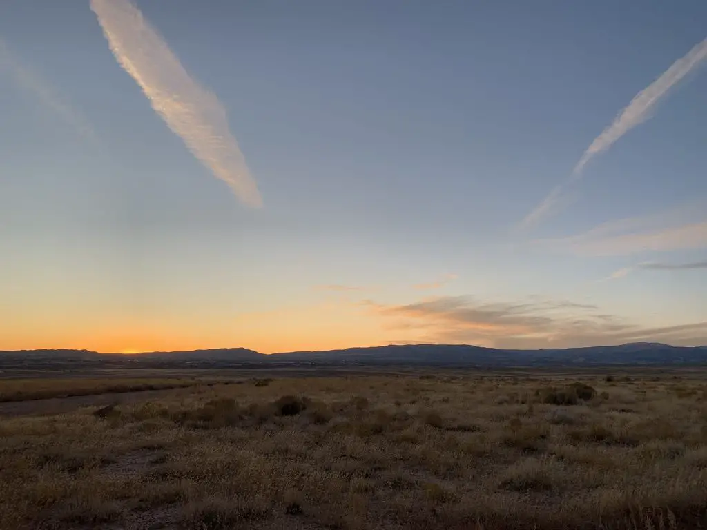 Sunset over a desert landscape with the silhouette of dark mountains in the background