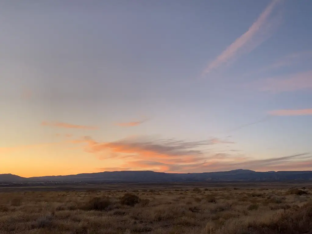 Sunset over a desert landscape with the silhouette of dark mountains in the background