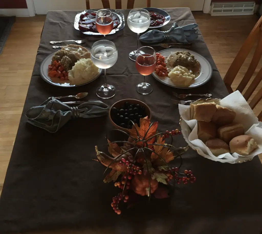 Table set with food such as potatoes, carrots, rolls, turkey and stuffing spread over it.
