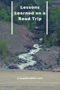 A creek flows down a rocky ravine, a small bridge crosses it. Pin reads, "Lessons Learned on a Road Trip"