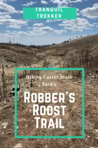 A path leads through brown-grass-covered hills and trees that appear burnt. Pin reads, "Hiking Custer State Park's Robber's Roost Trail"