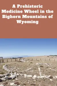 Small stones on the ground form the center and outer portions of a wheel with stone spokes connecting them. Pin reads, "A Prehistoric Medicine Wheel in the Bighorn Mountains of Wyoming"