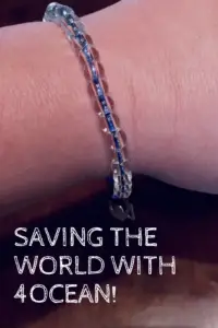 A blue bracelet with clear beads on a wrist. Pin reads, "Saving the World with 4Ocean!"