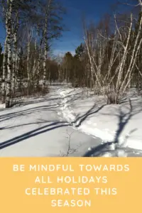 A footpath in the snow leads through leafless trees, all under a clear, blue sky. Pin reads, "Be mindful towards all holidays celebrated this season"