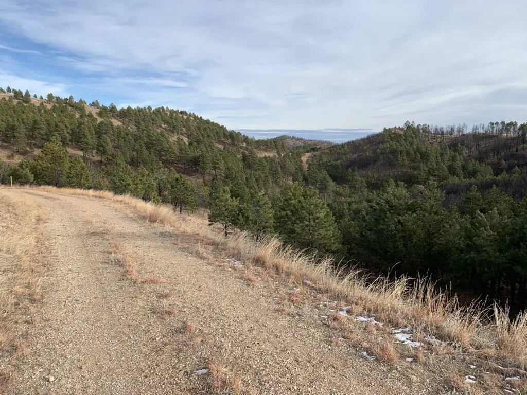 A gravel road with tree-covered hillsides in the distance