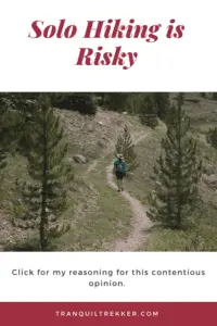 Rear view of a person walking along on a hiking trail, in a grassy area, between some trees. Pin reads, "Solo hiking is risky. Click for my reasoning for this contentious opinion."