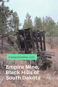 Wooden remains of a mine building in the woods. Pin reads, "Empire Mine, Black Hills of South Dakota".
