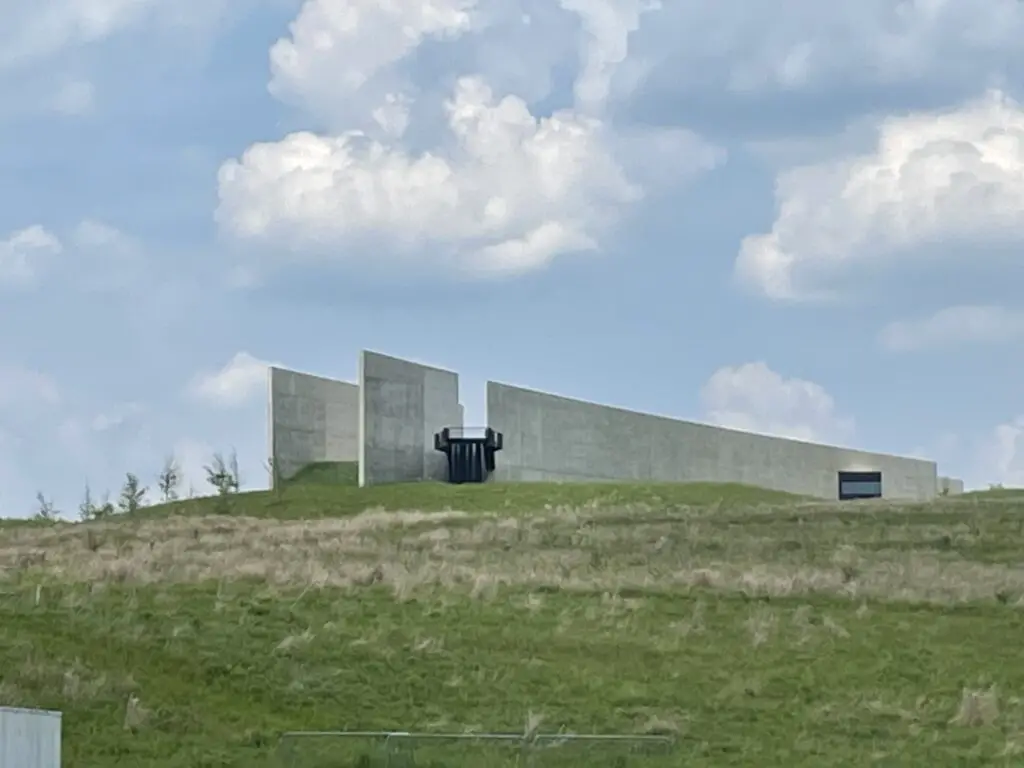View up a green-grass hill at a large, concrete building