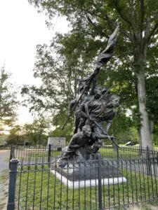 Iron sculpture of men with guns and holding a flag running