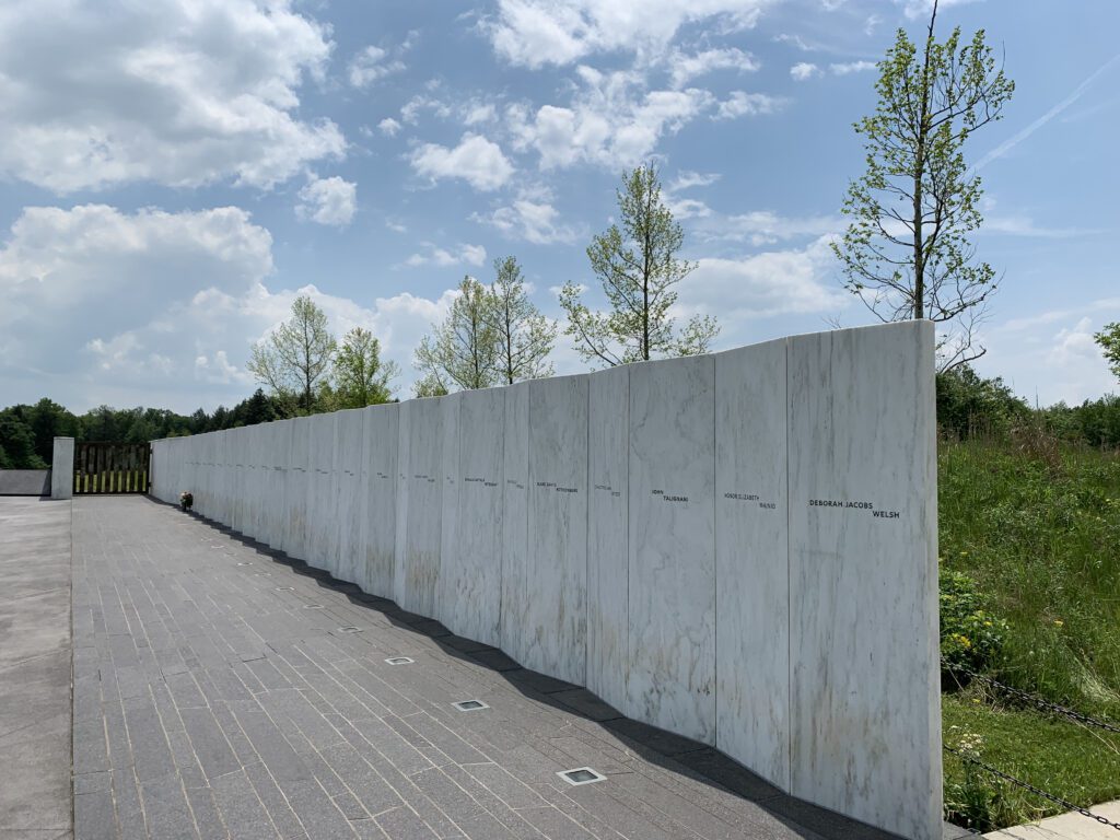 View down the length of a long, concrete wall with names written on it