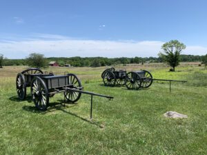 Two old, wooden wagons sit in a green grass field