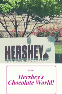 White sign reads, "Hershey" and has a chocolate kiss on it. Pin reads, "Visit Hershey's Chocolate World!"