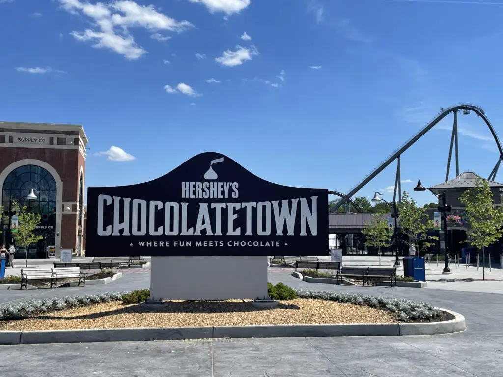 Large, brown sign reads, "Hershey's Chocolatetown where fun meets chocolate". A roller coaster is in the background