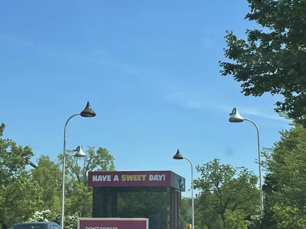 View through a window of several streetlamps that look like Hershey's Chocolate Kisses--some are wrapped in foil. A sign on a small building reads, "have a sweet day"