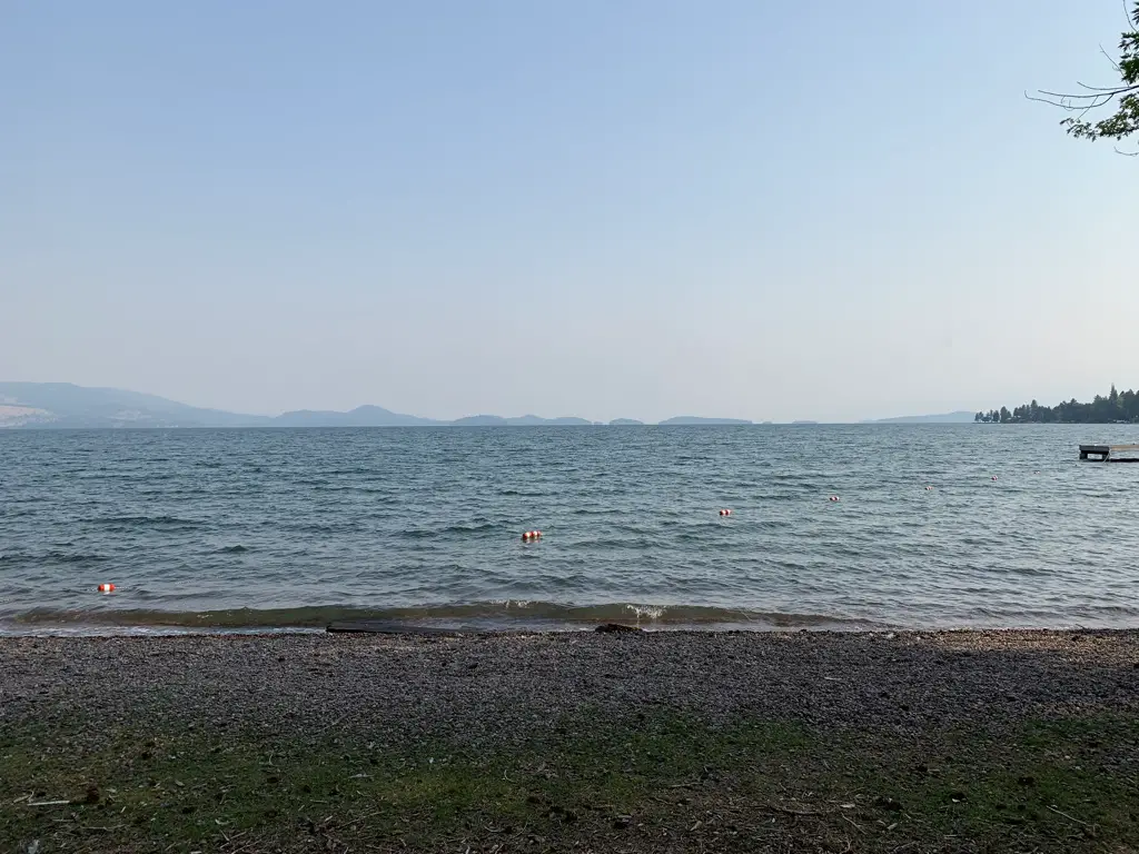 On a beach looking out over a large lake. Mountains are barely visible in the background through the haze.