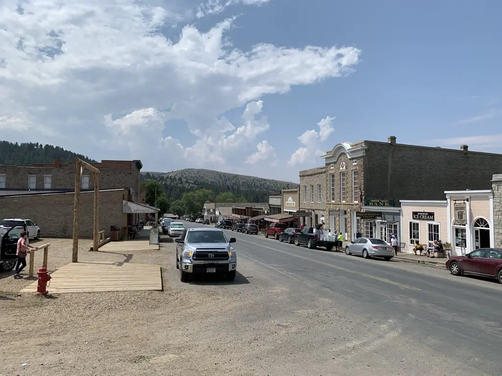 View down modern, paved, main street of Virginia City ghost town. Cars line both sides.