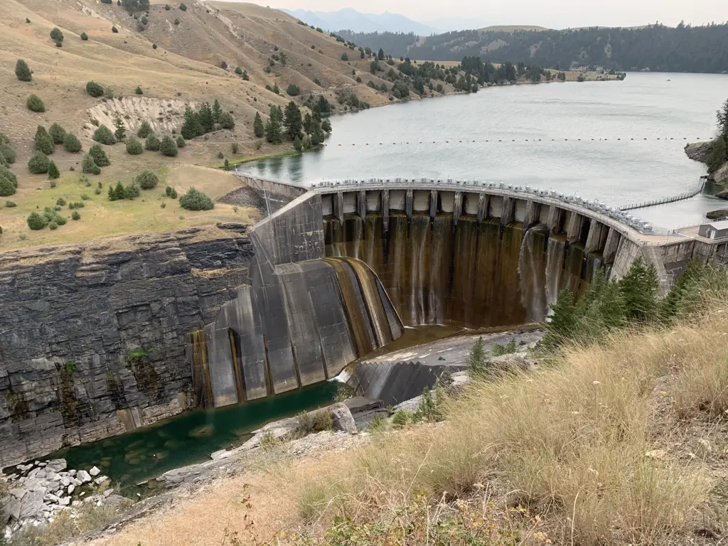 Large, concrete dam in a river canyon with a reservoir behind it