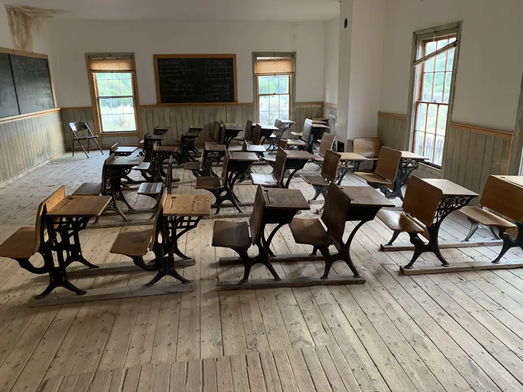 Interior of old, one room schoolhouse. Antique desks fill the room.