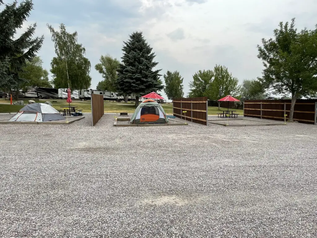 Three tent campsites separated by wood fences on gravel and pebble pads