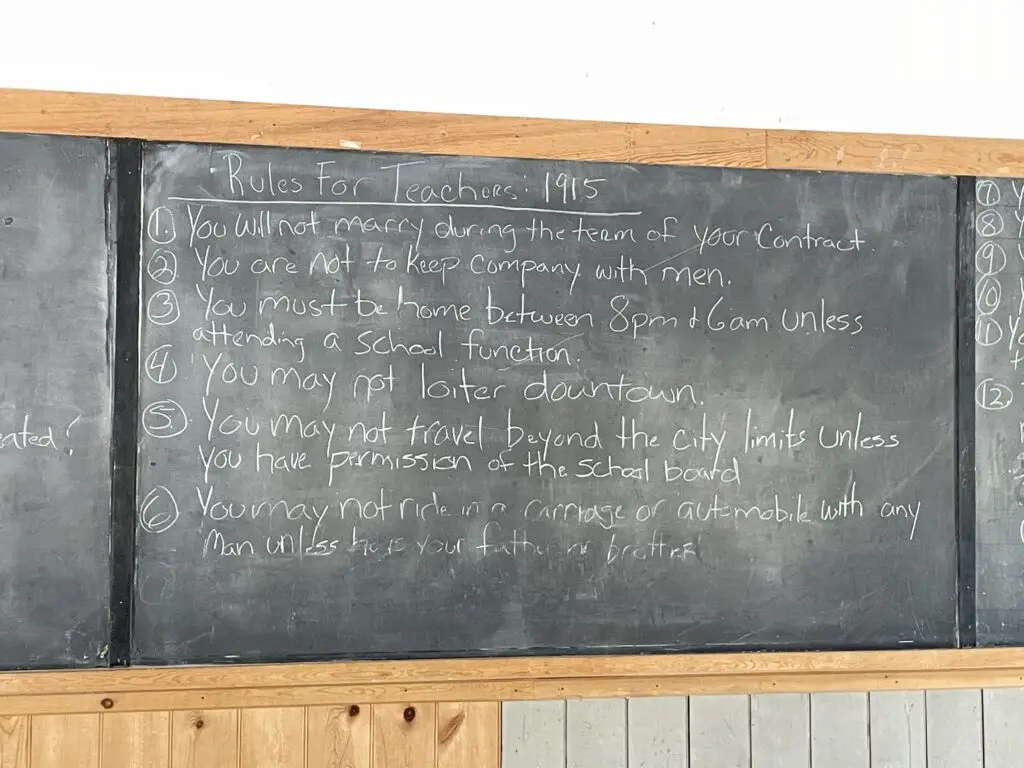 Rules for teachers at the schoolhouse in 1915 written on a chalkboard. These include, "you may no loiter downtown."