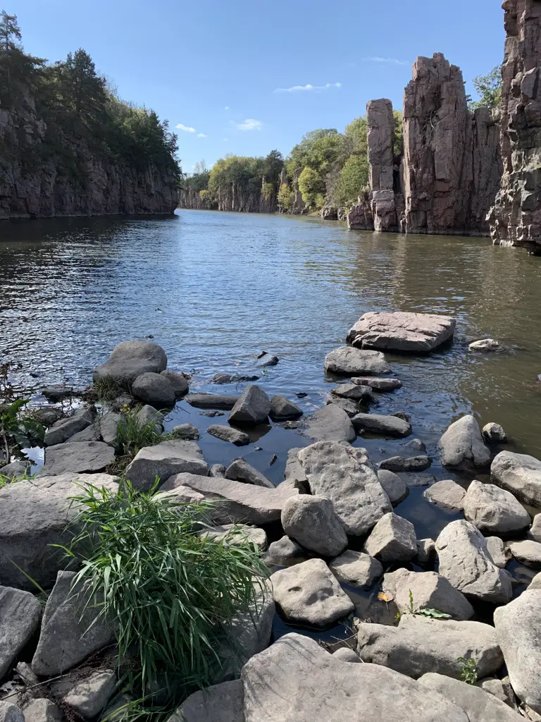 View down a creek with rocky and vegetation-covered walls on both sides, blue sky