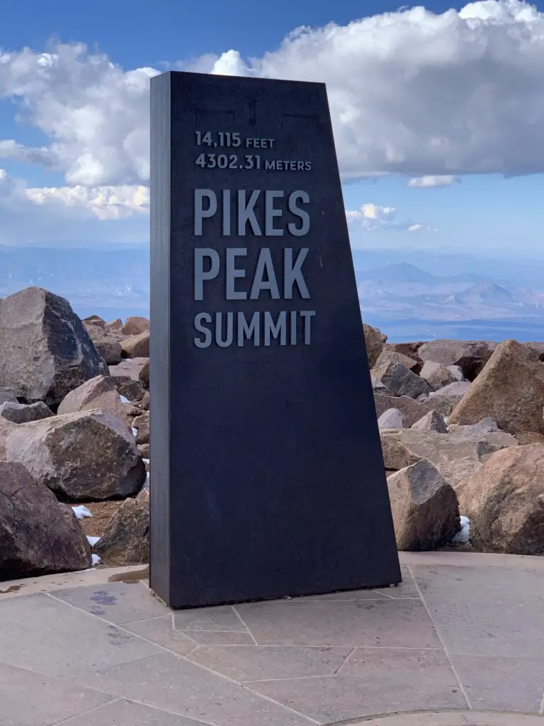 Black, stone sign that reads, "14,115 feet (4302.31 meters) Pikes Peak Summit"