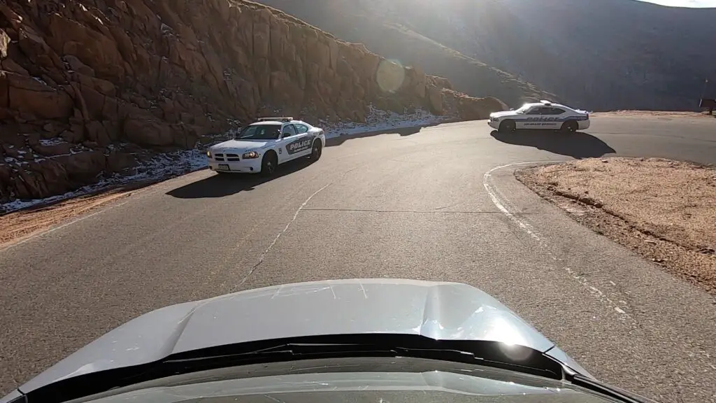 Two police cruisers round a curve in the road