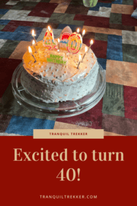 Birthday cake with "40", "Happy Birthday" and other lit candles sit on a table. Pin reads, "Excited to turn 40!"