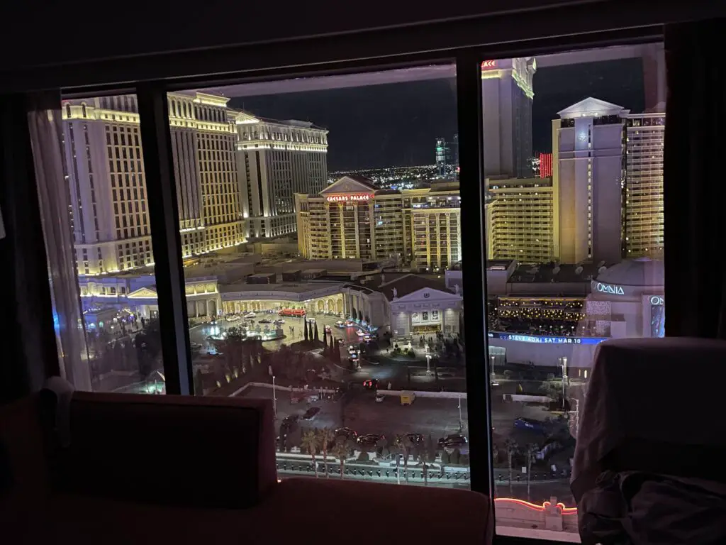 Nighttime view of the neon-lit casinos of Vegas through a hotel room window. 