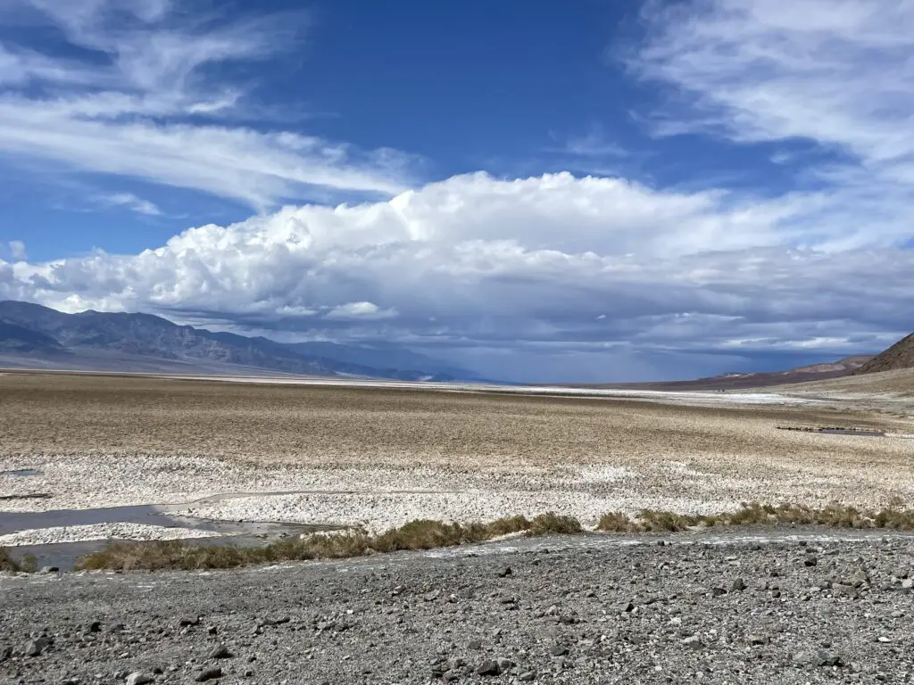 A rocky, salt-flat spreads to the horizon, surrounded by rocky mountains. 