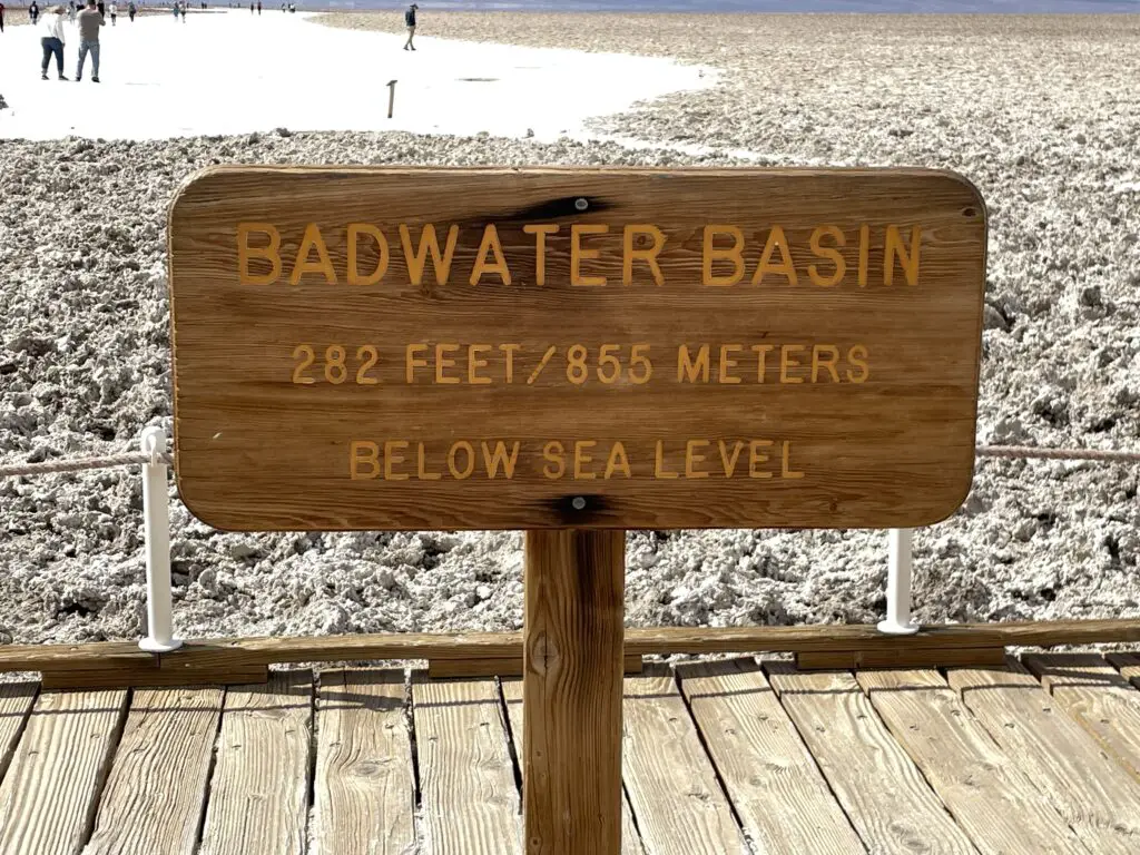 A sign on a boardwalk reads, "Badwater Basin, 282 feet/865 meters BELOW sea level!"