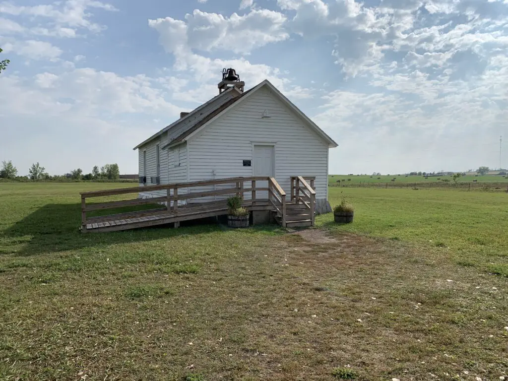 A white schoolhouse sits in a field