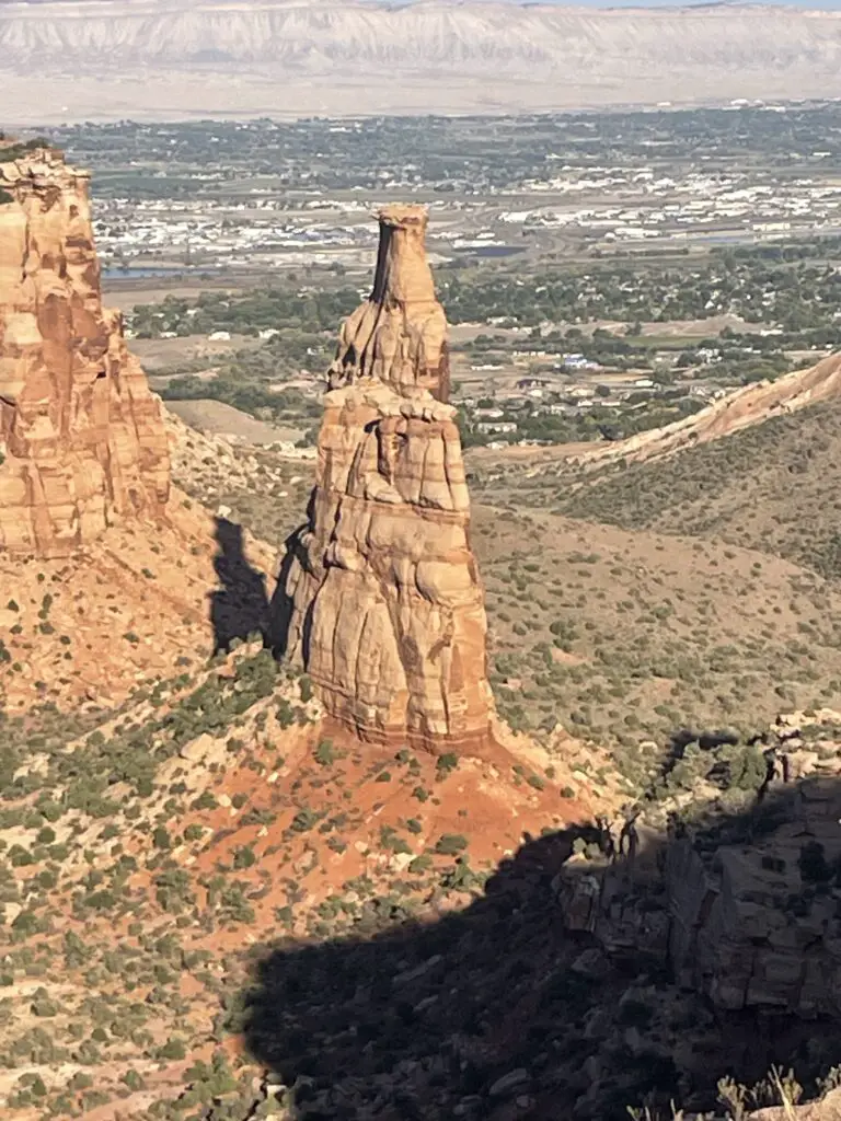 Brown rock monolith rises up from the scrub-brush covered canyon floor