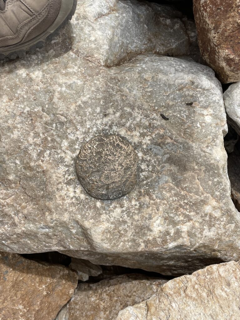 A close-up of a US geological survey benchmark set in a large rock.